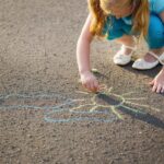child drawing with chalk on asphalt
